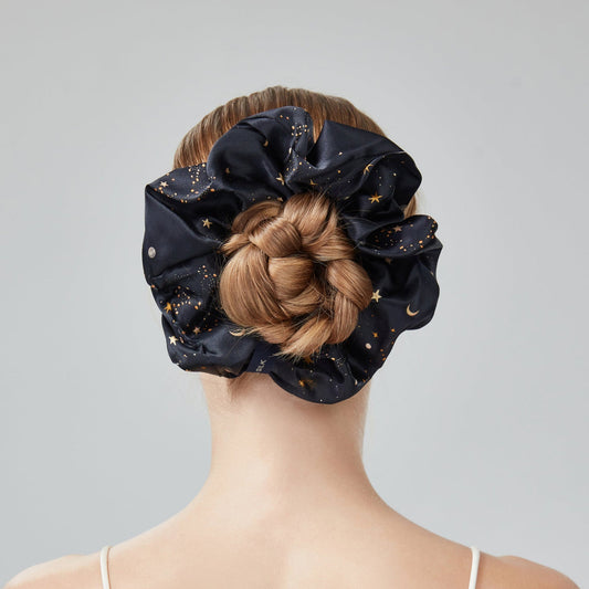 Person wearing a black scrunchie with braided hair on a gray background