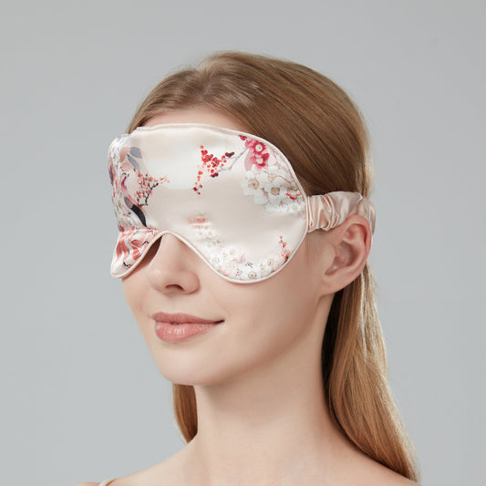 Woman wearing a floral sleep mask against a soft pink background