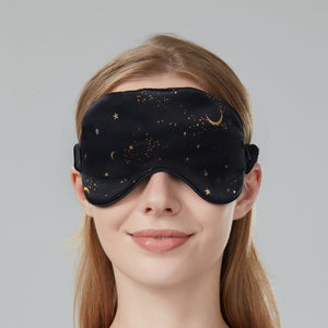 Woman wearing a black sleep mask with star and moon design on a dark navy background