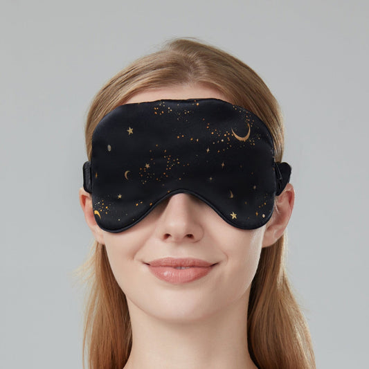 Woman wearing a black sleep mask with star and moon design on a dark navy background
