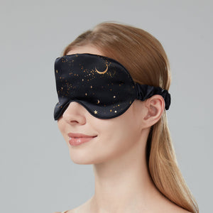 Woman wearing a black sleep mask with star and moon design on a gray background