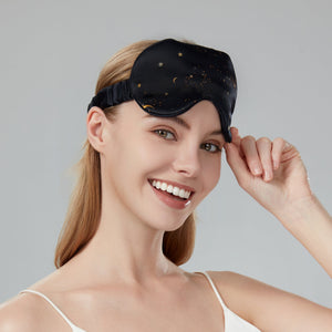 Woman wearing a black sleep mask with gold stars on a gray background