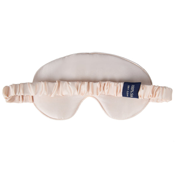 Pale pink sleep mask with a blue label on a white background